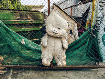 Abandoned stuffed toy hanging from chainlink fence