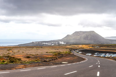 Road leading towards mountains against sky