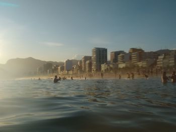 Buildings by sea against clear sky