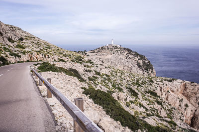 Scenic view of sea by mountain against sky