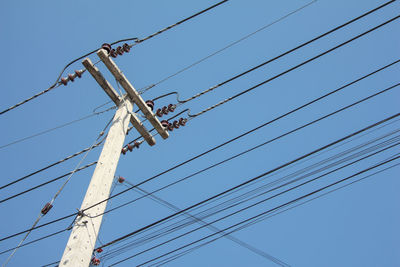 Low angle view of power lines against clear blue sky