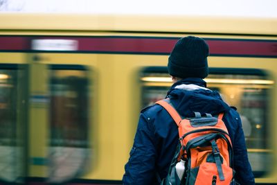 Rear view of man standing by train at railroad station