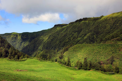 Scenic view of green mountains against cloudy sky at azores