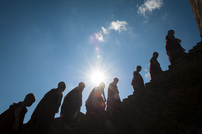 Low angle view of people standing against sky