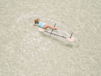 High angle view of girl relaxing in a transparent canoe in tropical waters