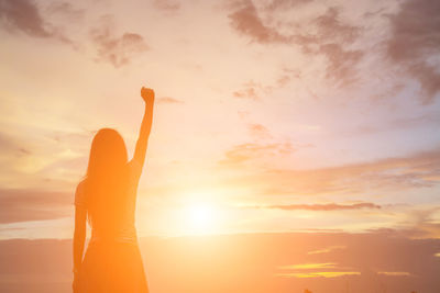 Midsection of woman standing against sky during sunset