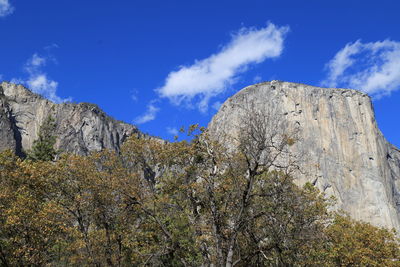 Low angle view of rocky mountain against blue sky