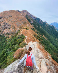 Rear view of girl sitting on rock against mountain