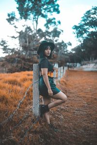 Young woman looking away while sitting on field