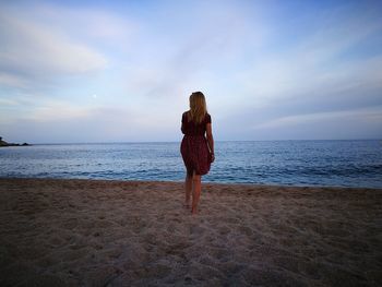 Rear view of woman standing on shore at beach