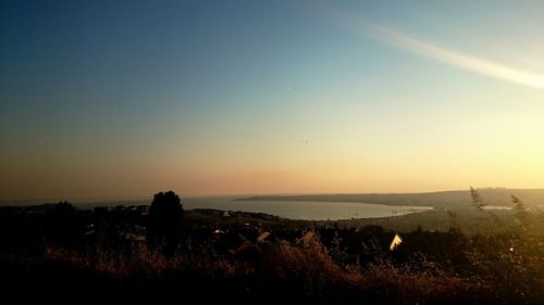 Scenic view of silhouette field against clear sky at sunset