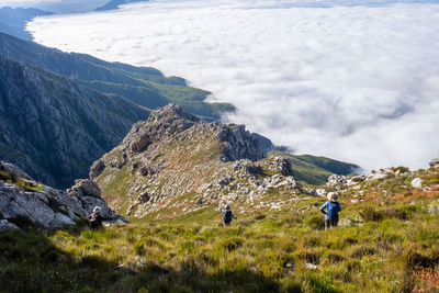 Three hikers looking at mountain ranges  and sea of clouds 