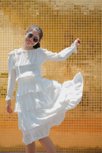 Portrait of smiling young woman standing against wall