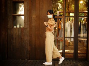 Side view of woman standing against the wall