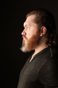 Portrait of man looking away against black background