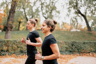 Side view of smiling woman running in park