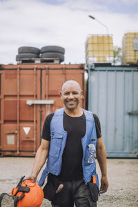 Portrait of happy bald construction worker with hardhat walking at site