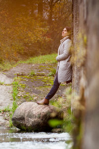 Side view of woman on rock in forest