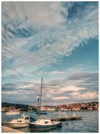 Boats in harbor against sky in city