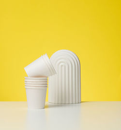 Paper cardboard white cups for coffee, yellow background. eco-friendly tableware, zero waste