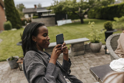 Smiling woman using phone in garden