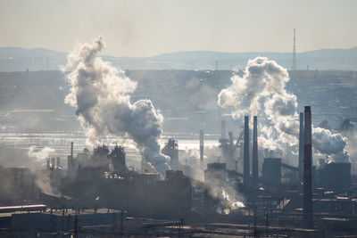 Smoke emitting from factory against sky