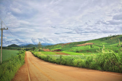 Road amidst field against sky