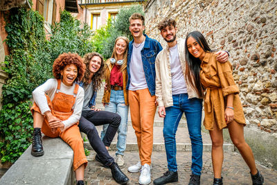 Portrait of smiling friends sitting on street