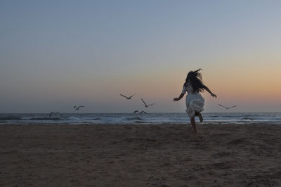 Woman on beach against sky during sunset