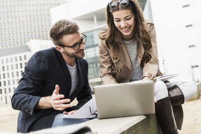 Young business couple working together outdoor, using laptop