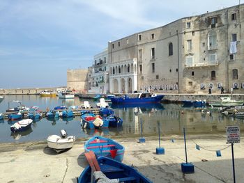 Boats moored in sea against buildings in city