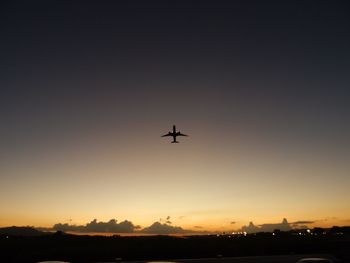 Low angle view of silhouette airplane against sky during sunset