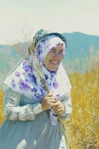 Portrait of smiling young woman standing against sky