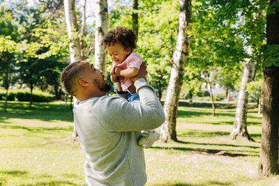 Father and son standing by plants against trees