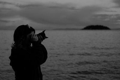 Young woman photographing sea against sky