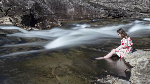 Woman standing on rock against waterfall