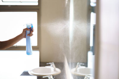 Midsection of woman holding umbrella in bathroom at home