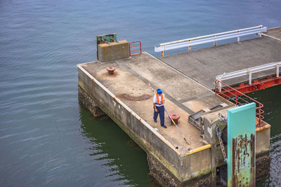 High angle view of man standing on railing by sea