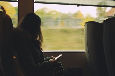 Rear view of woman looking through window