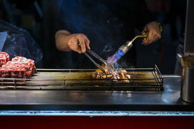 Midsection of chef grilling meat in kitchen