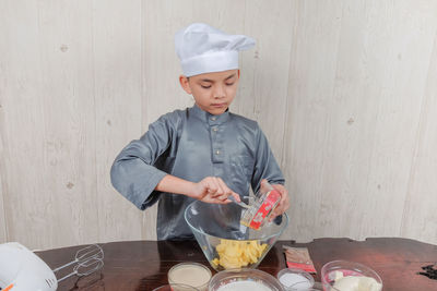 Boy holding ice cream in bowl on table