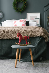 Vintage wooden toy horse stands on a stool in the christmas bedroom near the bed in dark colors