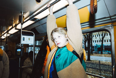 Girl holding handle while traveling in tram on weekend