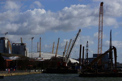 Cranes at commercial dock against sky