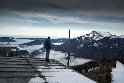 Rear view of man looking at snowcapped mountain against sky