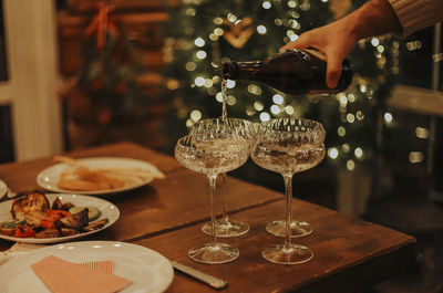 Midsection of woman holding wineglass on table