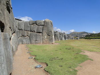 Stone wall on landscape against clear blue sky