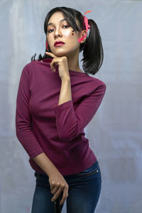 Young woman looking away while standing against wall