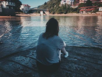 Rear view of woman standing by lake