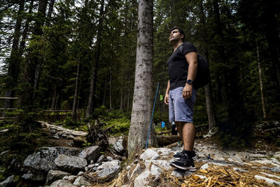 Full length of young man standing on rock in forest